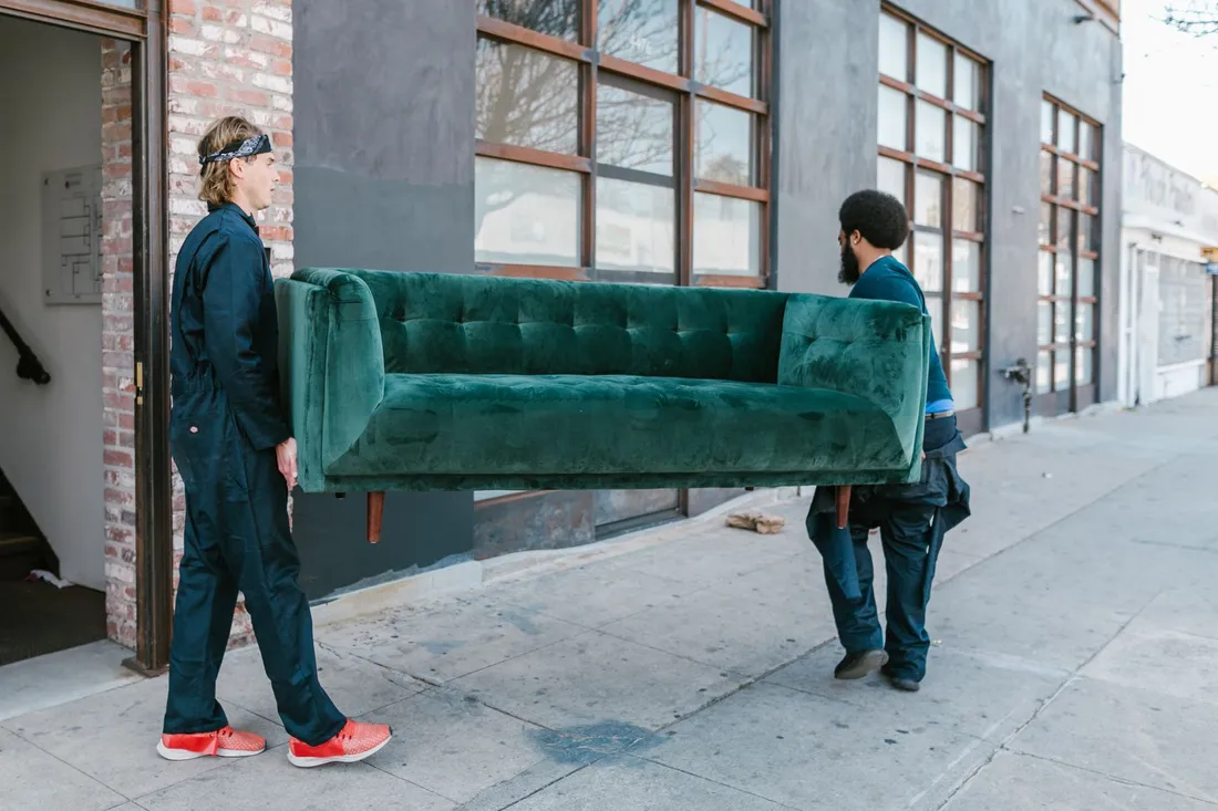 Umzugsteam von Global24 Umzüge trägt ein verpacktes Möbelstück zum Umzugswagen in Berlin